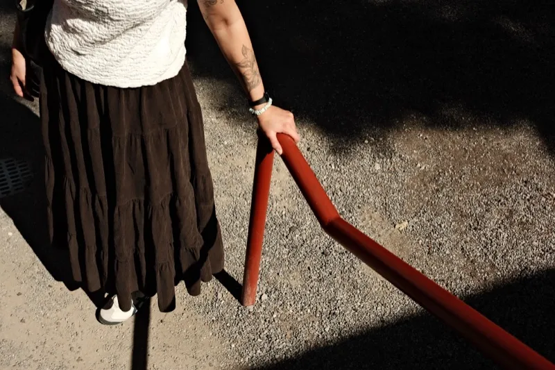 A person in a long skirt holding a red railing
